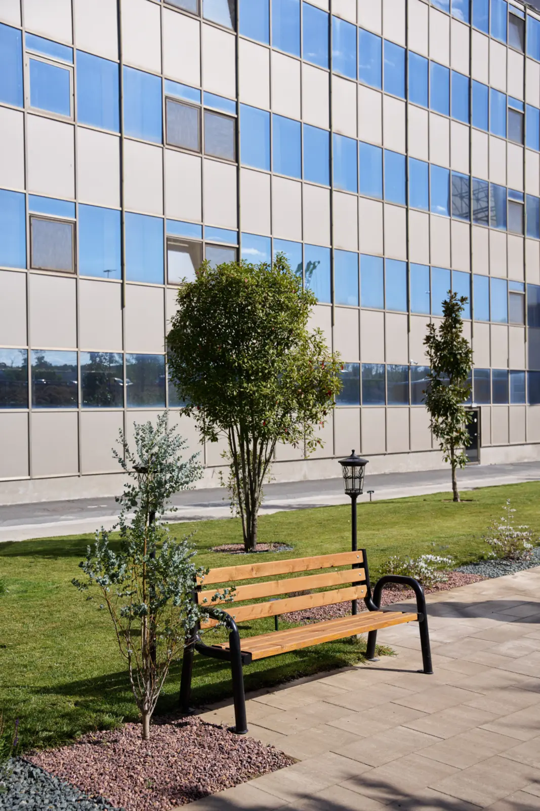 Bancă de parc din lemn și metal negru amplasată în grădina unui centru de îngrijire seniori, AsertivO Otopeni