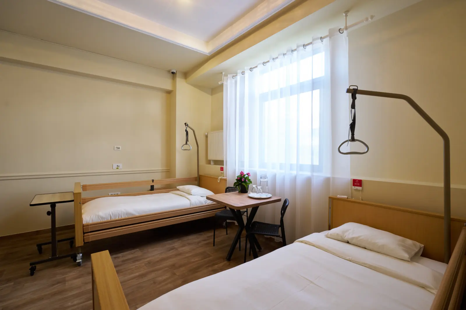 Cameră dublă luminoasă cu două saltele medicale reglabile, trapeze de ridicare, masă cu scaune, AsertivO Otopeni
