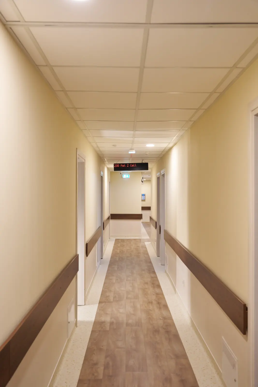 Coridor lung și bine iluminat al unui centru de îngrijire pentru seniori, cu pereți crem, AsertivO Otopeni