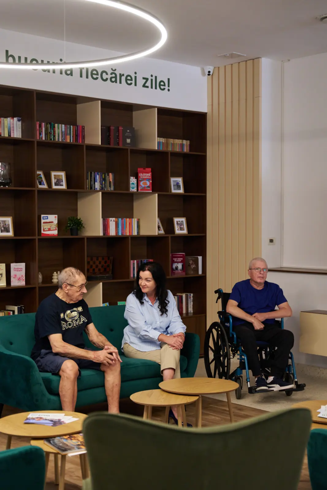 Doi seniori și o membră a personalului stând de vorbă în zona de relaxare a unui centru de îngrijire, AsertivO Otopeni