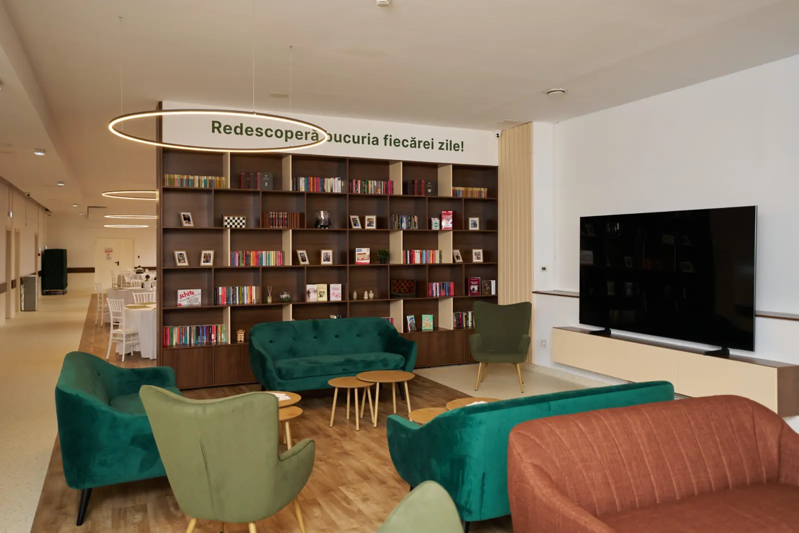 Sală de relaxare elegantă cu fotolii și canapele verzi de catifea, bibliotecă plină cu cărți, AsertivO Otopeni