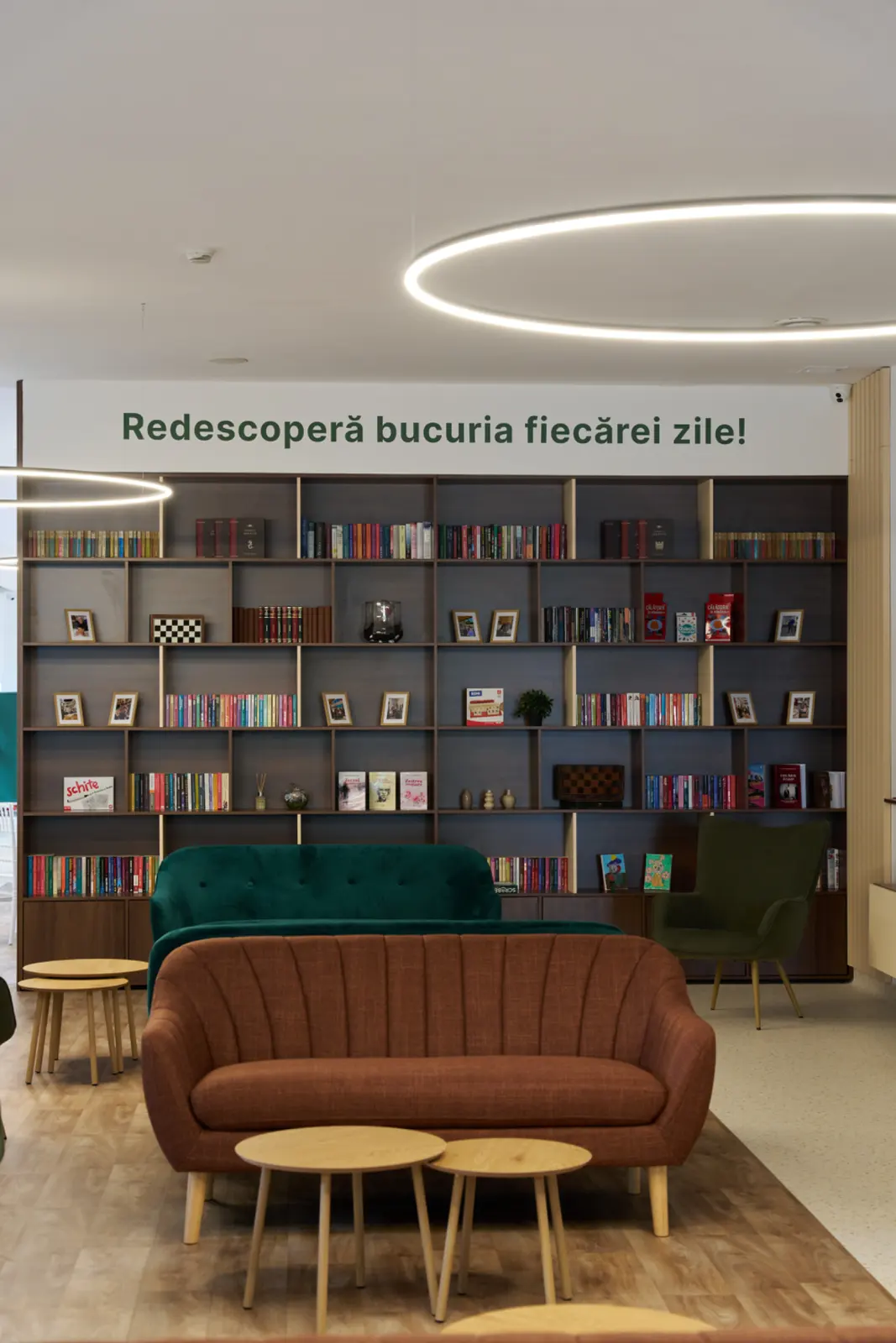 Zonă de relaxare dintr-un centru de îngrijire seniori din România, cu canapele verzi și maro, AsertivO Otopeni