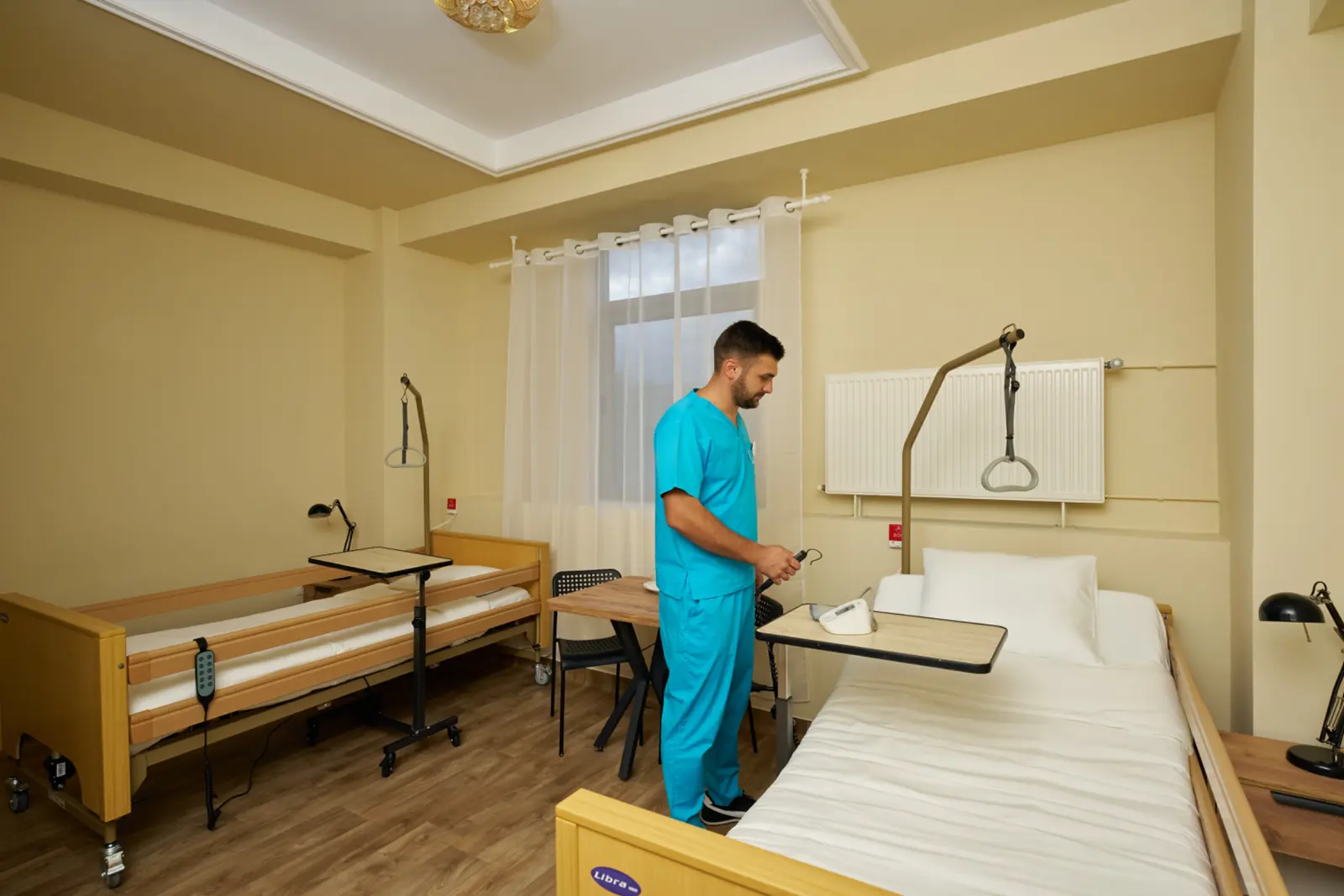 Asistent medical în uniformă turcoaz verificând echipamentul unei camere duble, AsertivO Otopeni